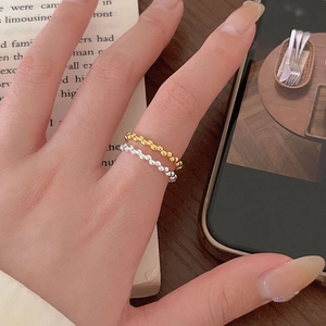 Close-up of stacked gold and silver beaded rings on a hand with an aesthetic background