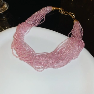 Detailed view of layered pink seed bead necklace with gold-plated lobster clasp and extension