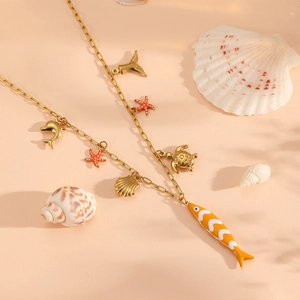Macro detail of ocean themed gold necklace with fish shell and starfish charms