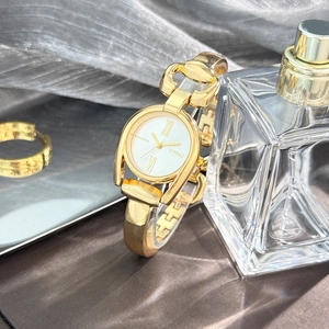 Detailed close-up of a vintage gold bracelet watch with roman numerals on a white dial