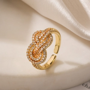 Elegant gold knot ring with shimmering zircon stones on silk and marble surface