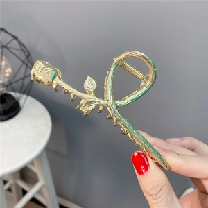 Dettaglio di un mollettone a forma di rosa vintage in lega dorata con smalto e strass