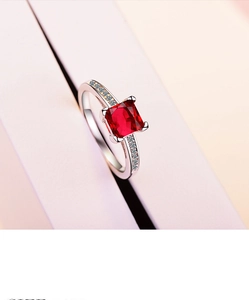 Close-up of square red zircon ring with four-prong setting and pavé side stones