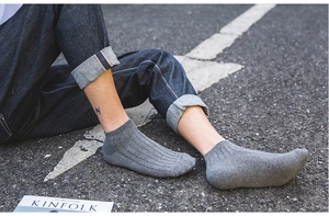 Close-up of grey low-cut knit socks with vertical texture on asphalt background