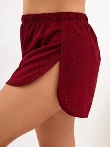 Detail view of burgundy eyelet lace shorts with elastic waist and curved side slits
