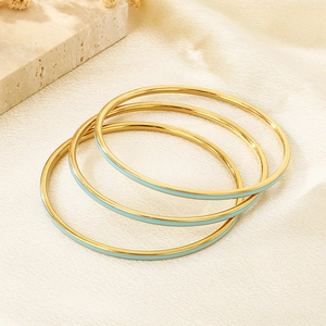 Detailed macro view of three stacked gold and light blue enamel stainless steel bangles