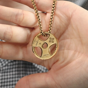 Detailed close-up of gold stainless steel dumbbell pendant with engraved fitness slogans
