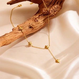 Elegant gold Y-shaped necklace with star charms on silk background for a stylish look