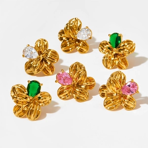Détail macro de boucles d'oreilles fleur avec pétales dorés et cristaux blancs et roses