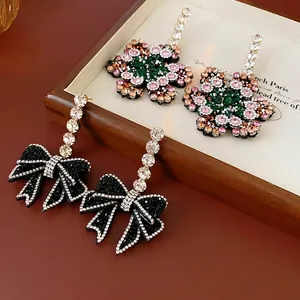Elegante Blumen- und Schleifenohrringe mit bunten Strasssteinen auf einem Holztablett