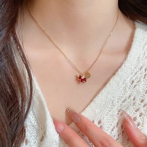Close-up of gold-plated necklace with red horse pendant and gold heart charm on model