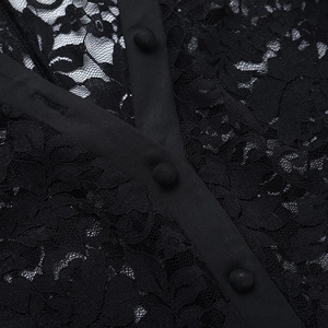 Close-up detail of floral lace fabric and matching fabric-covered buttons on black top
