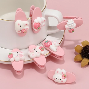 Cute pink bunny and strawberry hair clips on a pastel background with decorative teacup