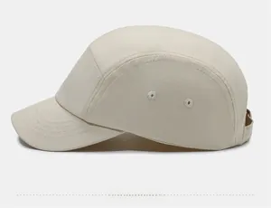 Side view of beige five-panel cap with metal eyelets and reinforced brim stitching