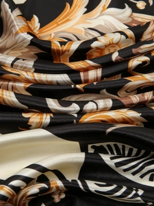 Macro shot of silk texture with baroque pattern in black, gold and beige tones