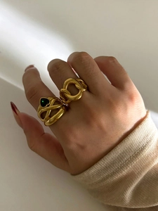 Detail of gold chain ring and heart-shaped green gemstone ring on model hands