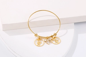 Detail of 18k gold plated stainless steel bracelet with boy, girl and heart charms