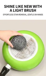 Macro shot of a stainless steel scouring pad cleaning stubborn stains on a green frying pan