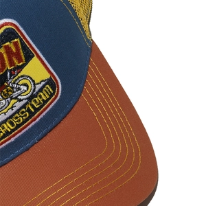 Detail of embroidered Cross Team patch and contrast yellow stitching on trucker hat
