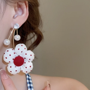 Detailed macro view of floral fabric earring with red dots, pearls and gold finish