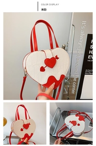 Macro view of creamy white heart bag with crocodile texture and red contrast details