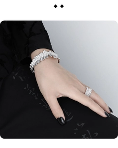 Close-up of pleated sterling silver bracelet and ring set with sparkling diamonds on wrist