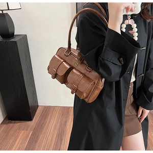 Detail of a brown vintage Boston bag showing textured leather and front buckle pockets