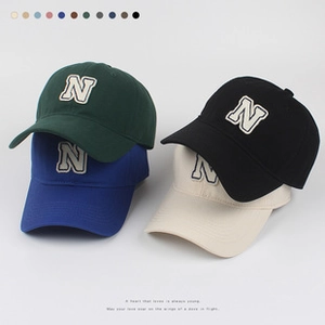 Close-up of stacked breathable baseball caps with letter N embroidery in four colors