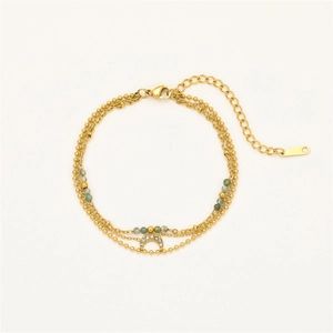 Detail of a triple-layer gold bracelet with moon pendant, stone beads, and metal accents