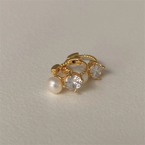 Macro view of gold twisted earrings with cubic zirconia and shiny white pearls