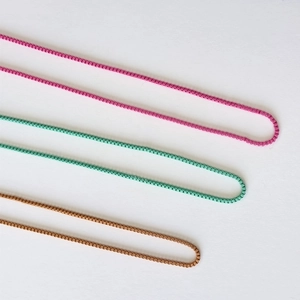 Detailansicht bunter Box-Ketten in Rosa, Minzgrün und Bronze für geschichtete Looks