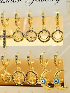 Close-up of golden hoop earrings featuring colorful rhinestone charms and cross symbols