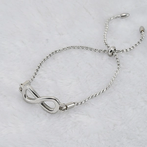 Detail of silver infinity symbol bracelet on white faux fur background with adjustable chain