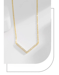 Macro shot of gold V-shaped pendant necklace with clear pave-set crystal stones