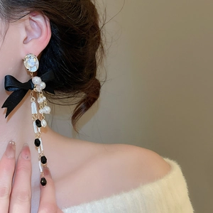 Detail of elegant pearl tassel earring with black silk bow and crystals on model