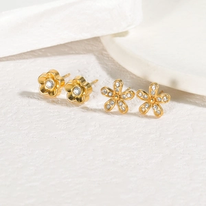 Detailed macro shot of gold plated floral earrings with clear zircon stones on stone background