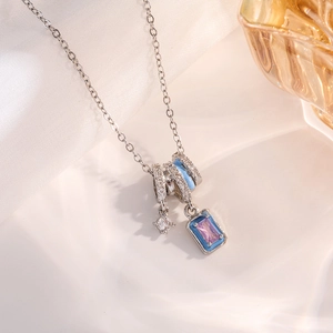 Macro view of blue enamel and crystal charms on a silver necklace with silk background