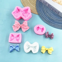 Detail of pink silicone molds and colorful fondant bows on a light blue background