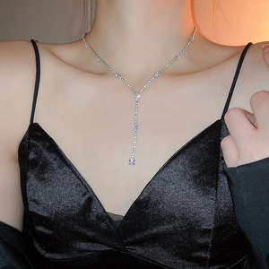 Detailed view of silver Y-shaped tassel necklace with sparkling drop pendant on model