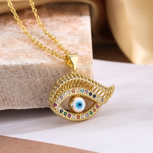 Macro view of gold evil eye pendant necklace with colorful crystals on marble
