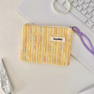 Nahaufnahme der gelb gestreiften Stricktasche mit lila Kordelzug auf einem Schreibtisch