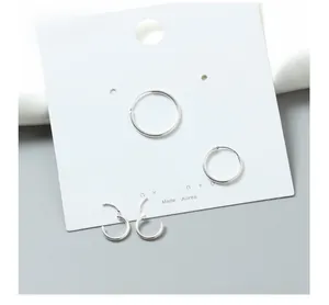 Macro detail of various sized S925 sterling silver hoop earrings on a minimalist display