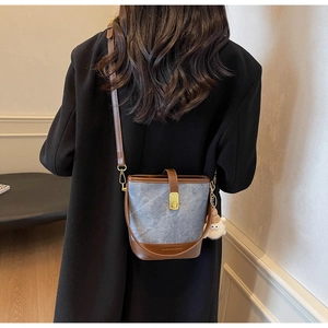 Close-up of retro bucket bag in grey-blue canvas and brown leather on black coat