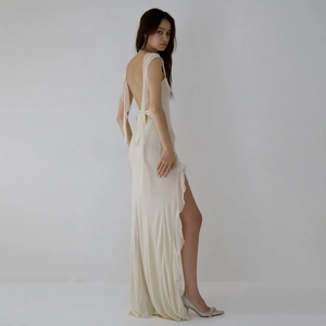 Detail of elegant cream backless maxi dress with side slit and delicate streamers