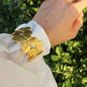 Chic 24k gold-plated butterfly cuff bracelet on a model with natural green background