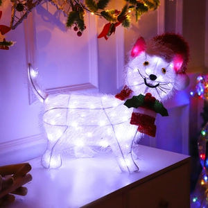 Macro detail of glowing white Christmas cat figure with red hat and festive scarf