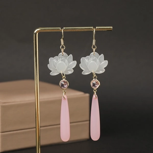 Macro detail of Chinese style fan pearl tassel earrings hanging on a golden metal display stand