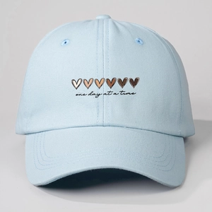 Light blue cotton baseball cap featuring gradient hearts and one day at a time text