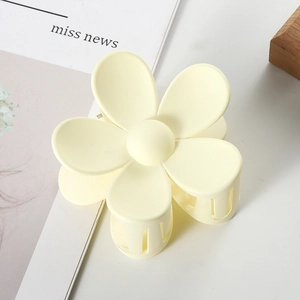 Macro view of matte cream flower hair claw clip with golden metal spring mechanism