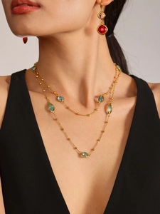 Detail einer eleganten goldenen Doppelkette mit blauen und roten Edelsteinakzenten